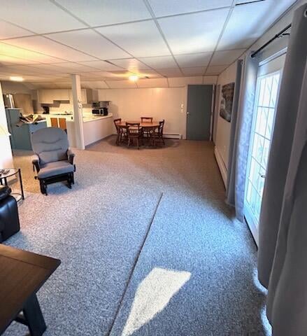 carpeted living room featuring a baseboard radiator and a drop ceiling