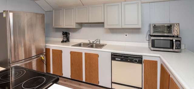 kitchen featuring white cabinets, sink, vaulted ceiling, light hardwood / wood-style flooring, and stainless steel appliances