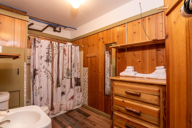 bathroom with wooden walls, hardwood / wood-style floors, and toilet