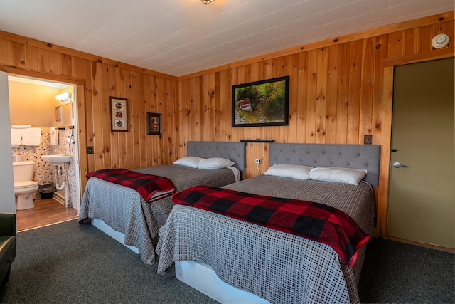 carpeted bedroom with ensuite bathroom and wood walls