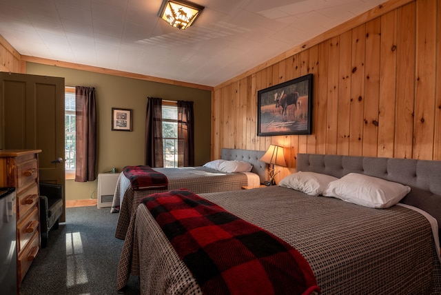 carpeted bedroom with wood walls and crown molding