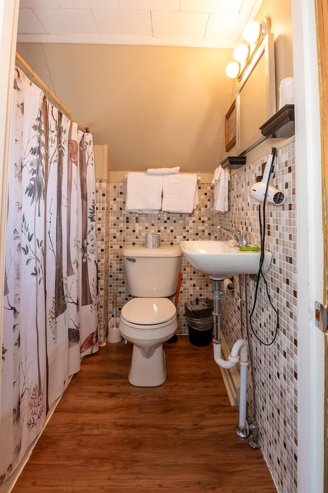 bathroom with decorative backsplash, wood-type flooring, tile walls, and toilet