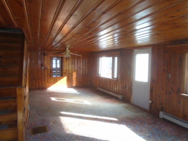 carpeted empty room with ceiling fan, wood ceiling, wooden walls, and a baseboard radiator