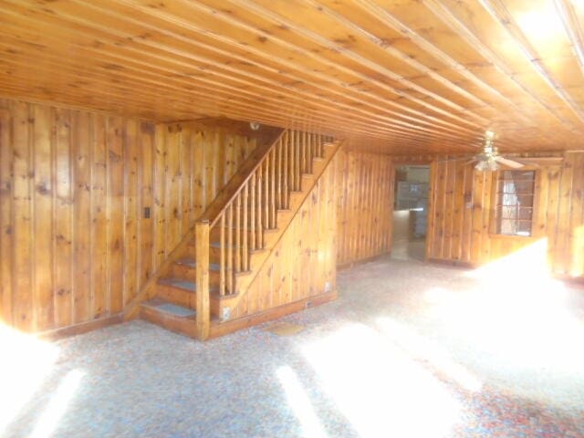 basement featuring wood walls and ceiling fan