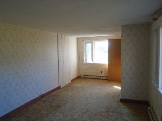 empty room featuring a baseboard radiator and light colored carpet