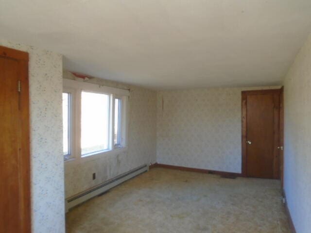 unfurnished room featuring baseboard heating and light colored carpet