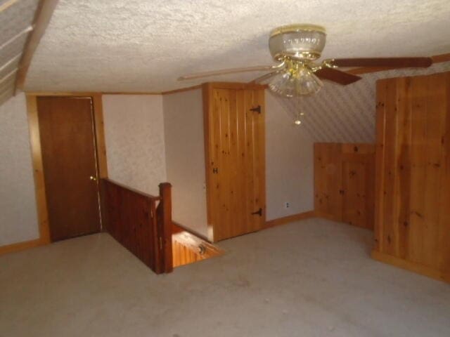 additional living space featuring a textured ceiling and wooden walls