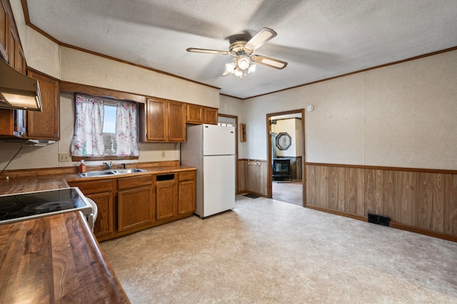 kitchen with a textured ceiling, ceiling fan, sink, white refrigerator, and stacked washer and clothes dryer