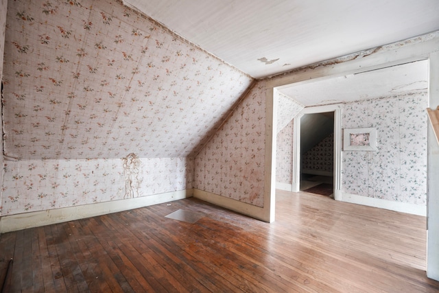 additional living space with hardwood / wood-style floors and vaulted ceiling