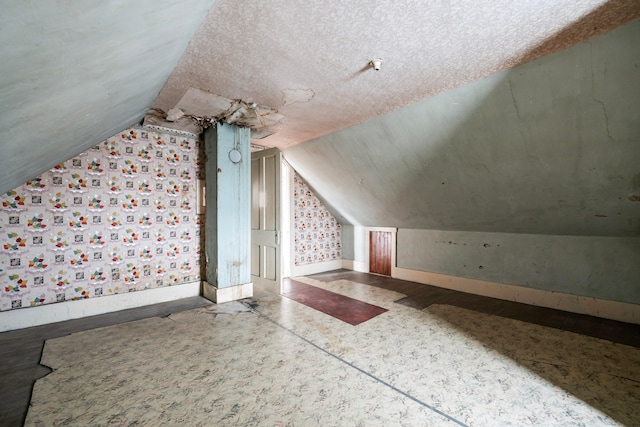 additional living space featuring a textured ceiling and lofted ceiling