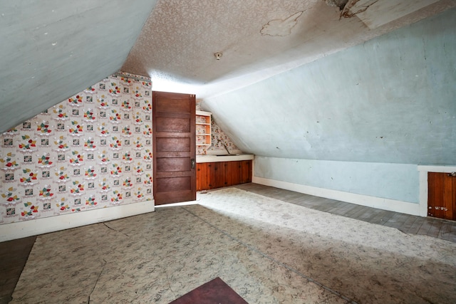 additional living space featuring a textured ceiling and vaulted ceiling