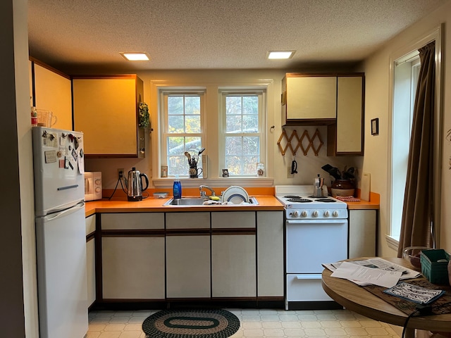 kitchen featuring sink, white appliances, and a textured ceiling