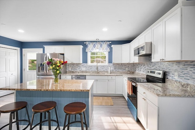 kitchen with stainless steel appliances, a kitchen island, and a healthy amount of sunlight