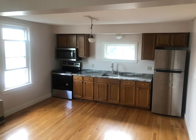 kitchen with stainless steel appliances, light hardwood / wood-style flooring, a healthy amount of sunlight, and sink