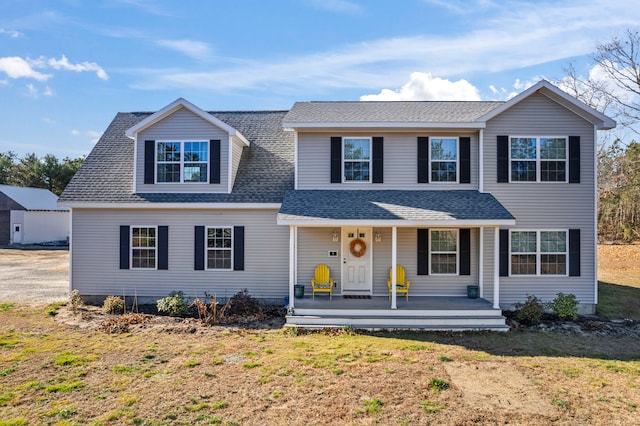 front facade featuring covered porch and a front yard