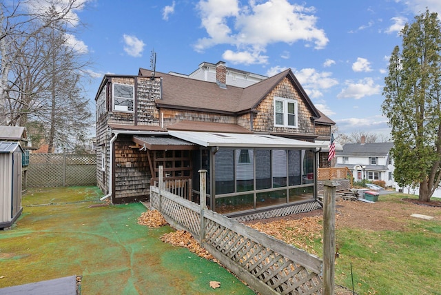 back of house featuring a lawn and a sunroom