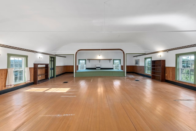 unfurnished living room with wooden walls and light hardwood / wood-style flooring