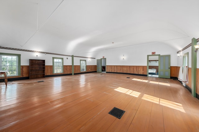 unfurnished room featuring light hardwood / wood-style flooring, lofted ceiling, and wood walls