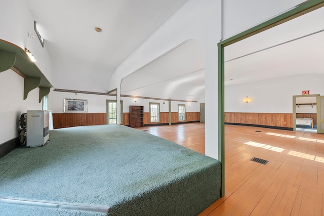 interior space featuring heating unit, wood walls, high vaulted ceiling, and wood-type flooring