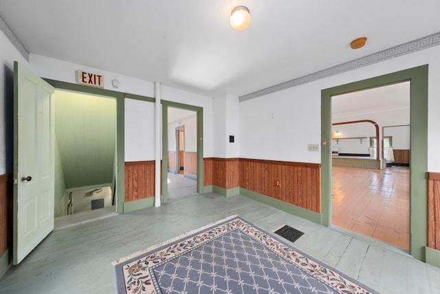 hall featuring wood walls, light hardwood / wood-style floors, and crown molding