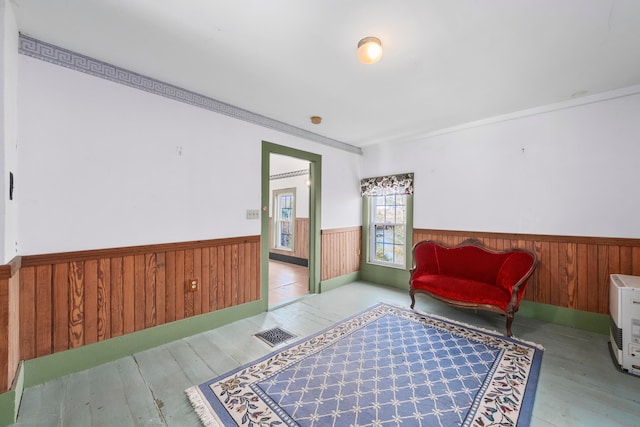 sitting room featuring ornamental molding, light hardwood / wood-style floors, and wooden walls