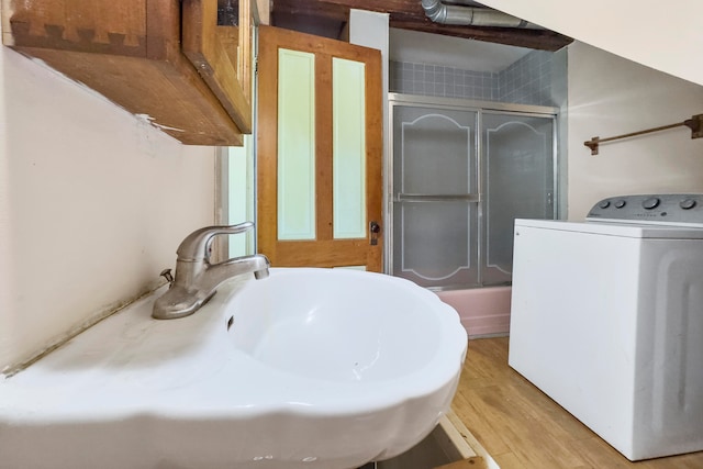 bathroom with shower / bath combination with glass door, hardwood / wood-style flooring, and washer / dryer