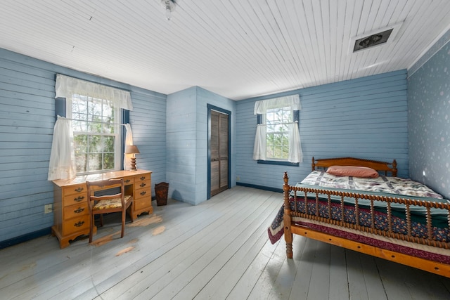 bedroom featuring light hardwood / wood-style floors, a closet, and wood walls