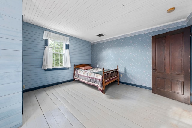 unfurnished bedroom with light hardwood / wood-style floors and wooden walls