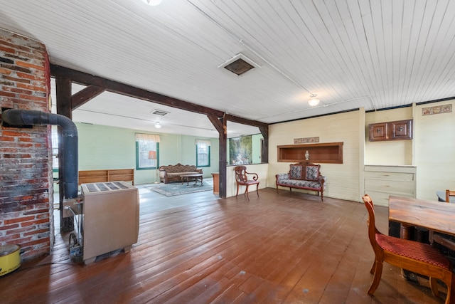 living room featuring beam ceiling, wood walls, and dark wood-type flooring