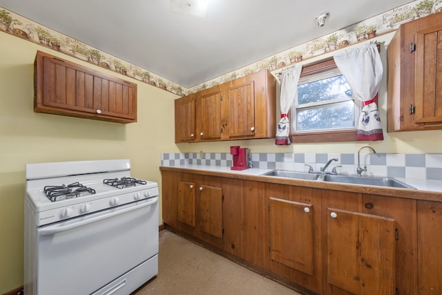 kitchen with decorative backsplash, sink, and gas range gas stove