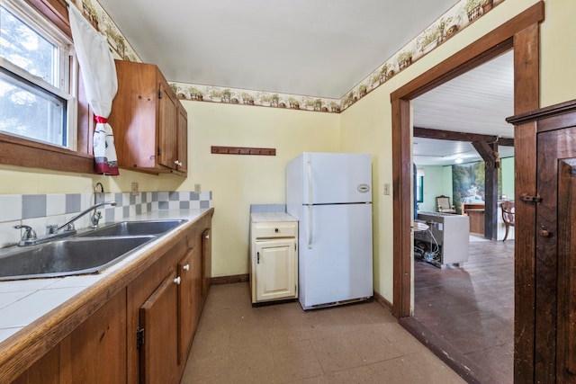 kitchen with white fridge, tile counters, and sink