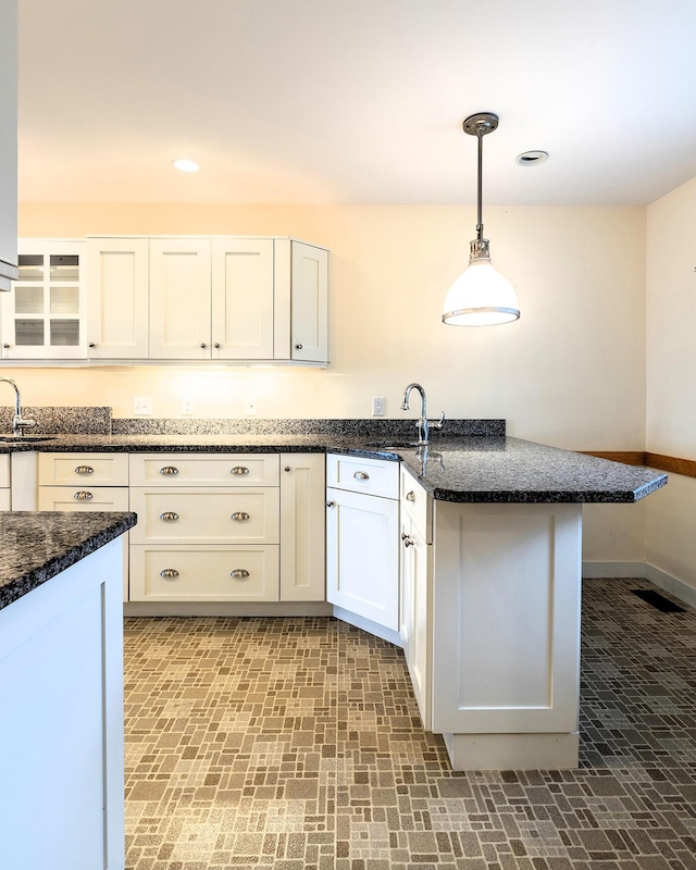 9 Jameson Point Rd Unit 10, Rockland, ME 04841 - kitchen with a peninsula, brick patterned flooring, white cabinets, hanging light fixtures, and dark stone counters