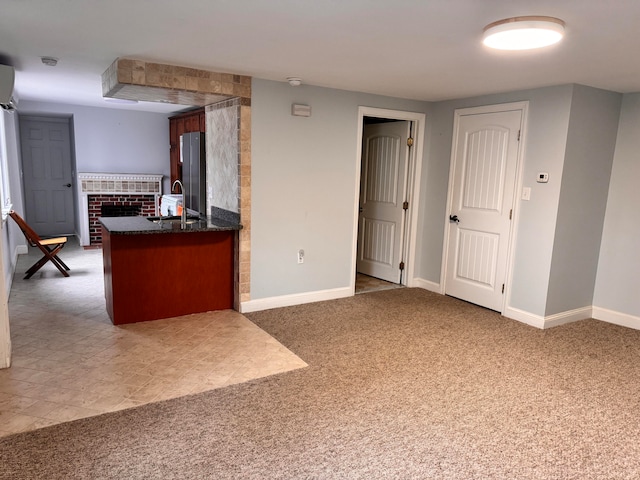 kitchen with stainless steel refrigerator, sink, a brick fireplace, kitchen peninsula, and carpet