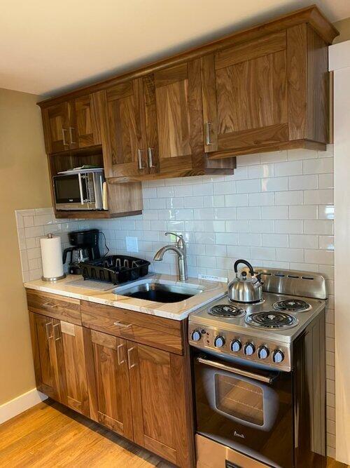 kitchen featuring tasteful backsplash, sink, stainless steel appliances, and light wood-type flooring