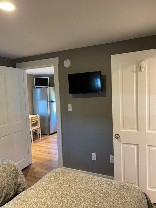 bedroom featuring stainless steel fridge and hardwood / wood-style flooring