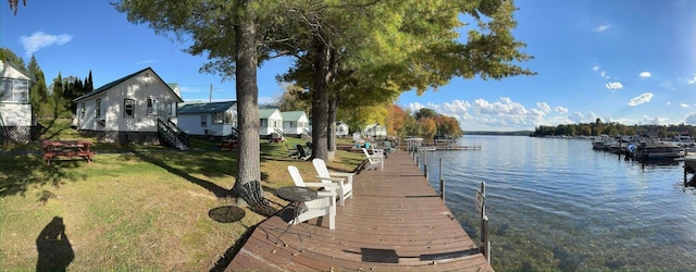 view of dock with a water view and a lawn