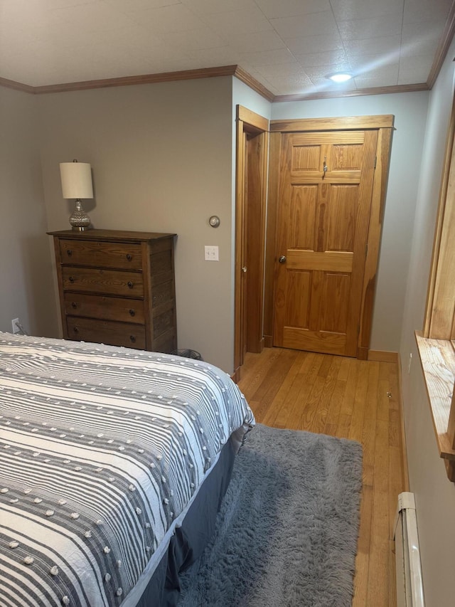 bedroom featuring baseboard heating, crown molding, and light wood-type flooring