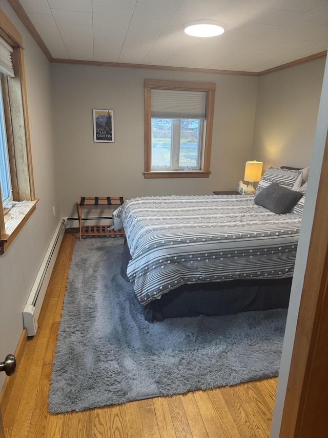 bedroom featuring a baseboard radiator, ornamental molding, and light hardwood / wood-style flooring