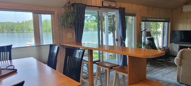 47 Fickett Dr, Litchfield, ME 04350 - dining area featuring vaulted ceiling, wooden walls, a water view, wood finished floors, and a wall unit AC