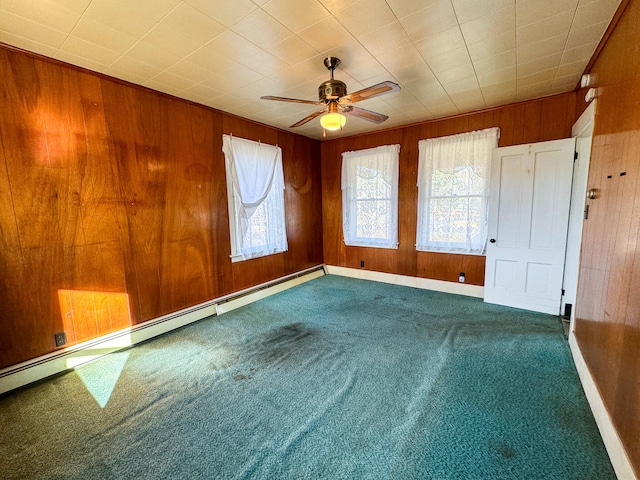 spare room featuring carpet floors, ceiling fan, a baseboard heating unit, and wood walls