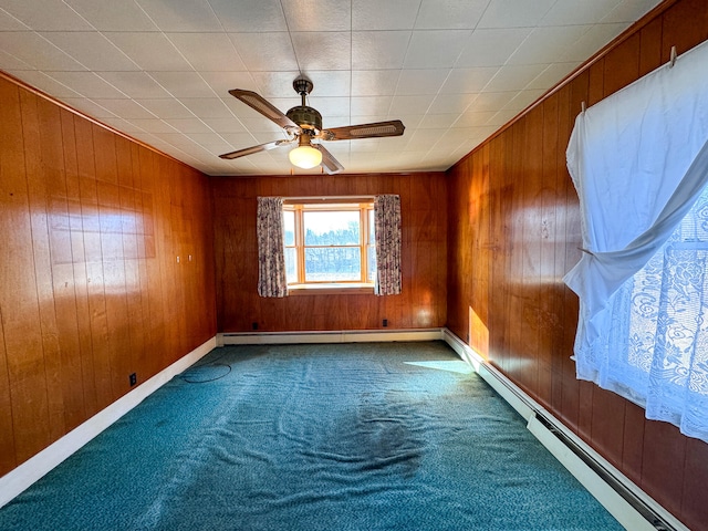 spare room featuring wood walls, carpet floors, and a baseboard heating unit