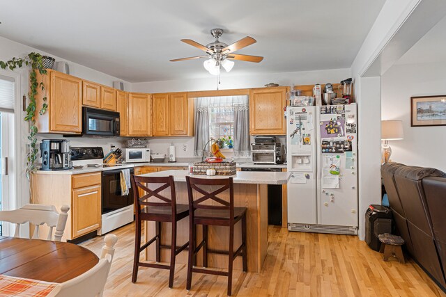 kitchen featuring ceiling fan, a center island, light hardwood / wood-style floors, white appliances, and a kitchen bar