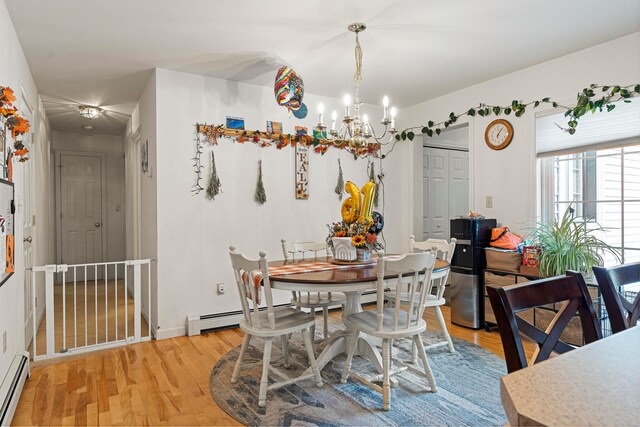 dining room with a baseboard radiator, a notable chandelier, and hardwood / wood-style flooring