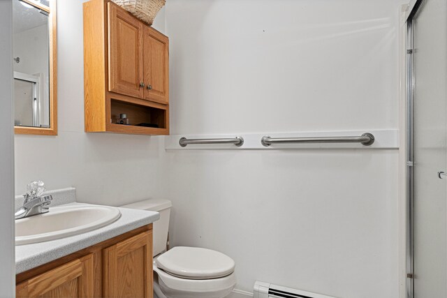 bathroom with vanity, a shower with shower door, a baseboard radiator, and toilet