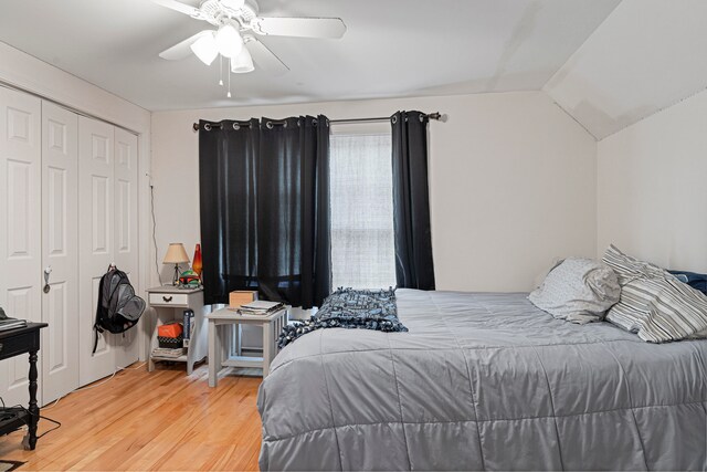 bedroom with a closet, light hardwood / wood-style floors, vaulted ceiling, and ceiling fan