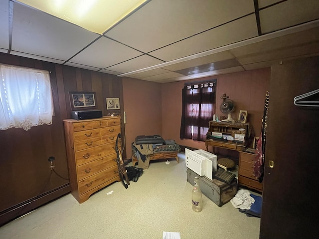 interior space featuring a paneled ceiling, wooden walls, and carpet flooring