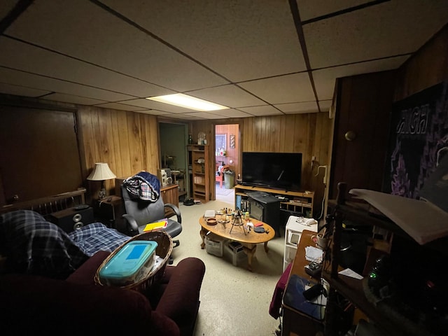 living room with a drop ceiling and wooden walls