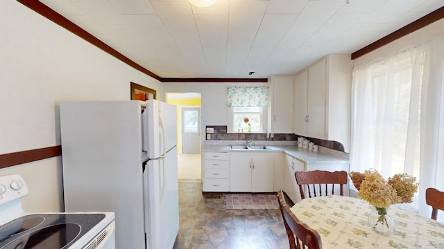 kitchen featuring white cabinets, stove, white fridge, and a healthy amount of sunlight