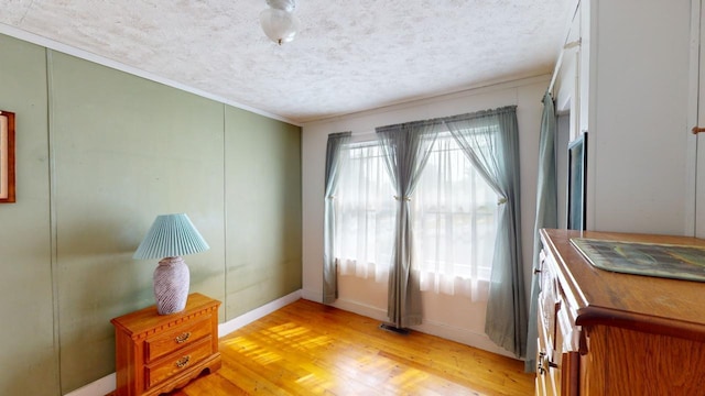 doorway featuring ornamental molding, a textured ceiling, and light wood-type flooring