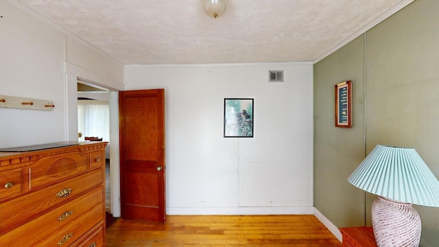 interior space featuring a textured ceiling, light hardwood / wood-style flooring, and ornamental molding